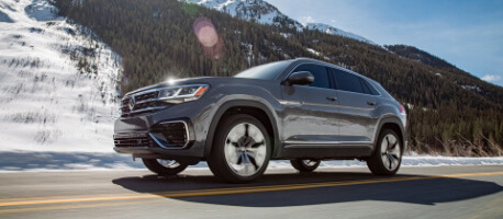 2023 Volkswagen Atlas Cross Sport driving on highway with mountains in the background