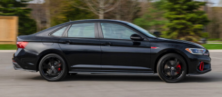 Black 2023 Volkswagen Jetta GLI driving down neighbourhood road