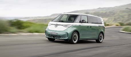 Green vw buzz driving on road near grass land