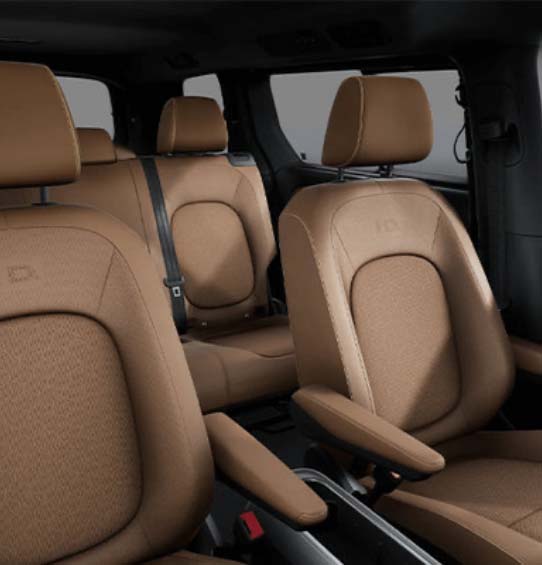 A view of the interior of the Volkswagen ID. Buzz 2025, showcasing the second row of seats with a brown leather upholstery and contrasting stitching.