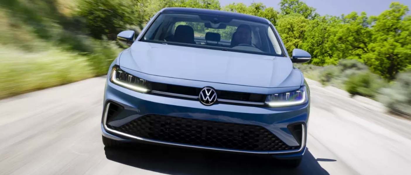 Blue 2025 Volkswagen Jetta driving down the road