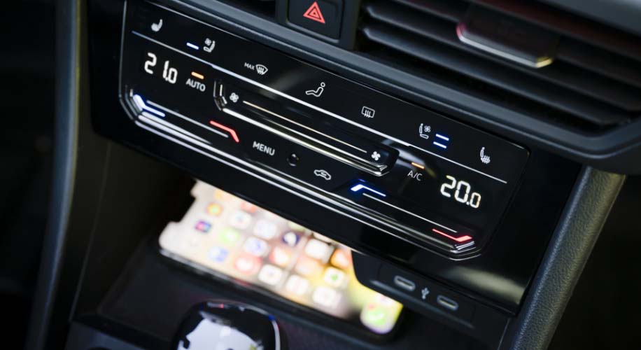 Close-up of the VW Jetta's center console, highlighting the wireless device charging area beneath the climate controls.