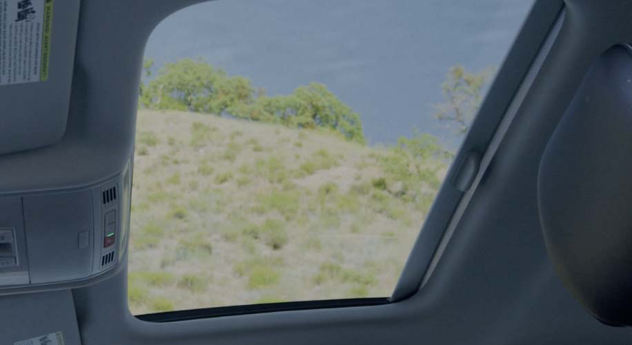 View through the Rail2Rail sunroof of the  Volkswagen Jetta, showing the sky and greenery outside.