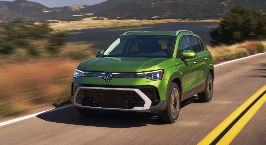 A green 2026 Taos driving down the road