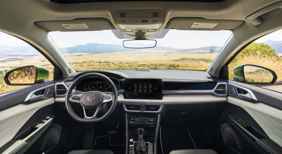 Interior view of the 2026 Volkswagen Taos, showing the dashboard, steering wheel, touchscreen display, and panoramic windshield.