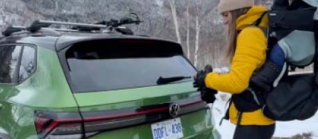 Person in yellow jacket ready to open 2026 Taos trunk