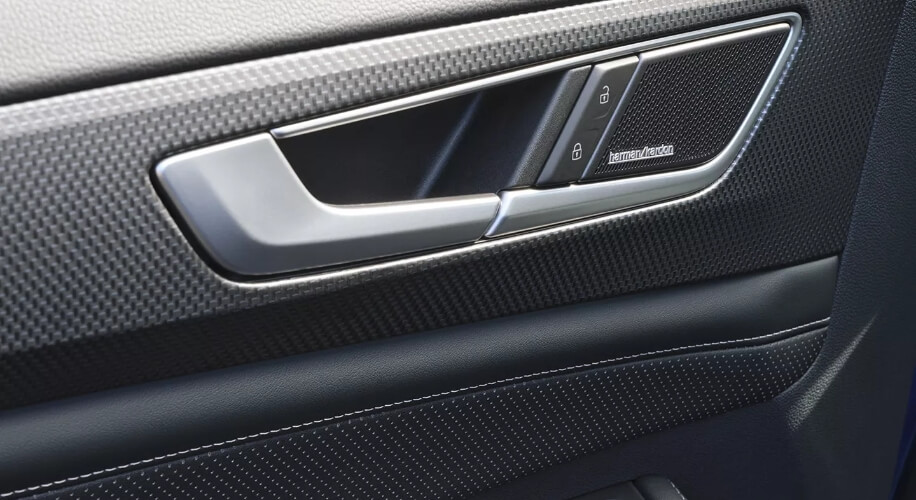 A close-up view of a Harman Kardon ® Premium Audio speaker system seamlessly integrated into the door panel of an Atlas Cross Sport.