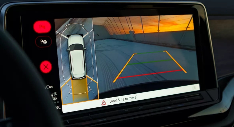 Atlas Cross Sport infotainment system displays a 360° area view with parking guidelines, showcasing the feature against a sunset backdrop.