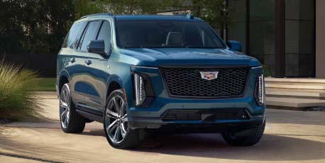 2025_cadillac_escalade_in_blue_suv_parked_in_front_of_modern_house_in_daylight