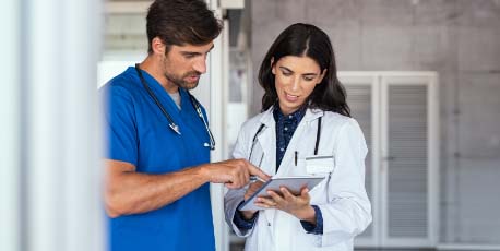 male_and_female_healthcare_professionals_reviewing_information_on_a_tablet_in_hospital_hallway