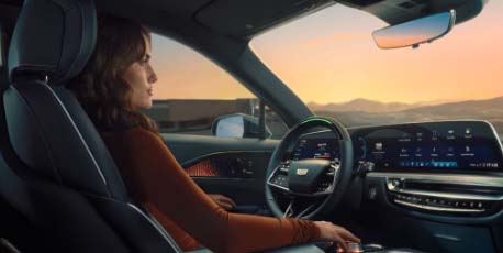 woman_sitting_in_driver_seat_of_modern_cadillac_during_sunset_with_ambient_lighting_and_digital_dashboard_display