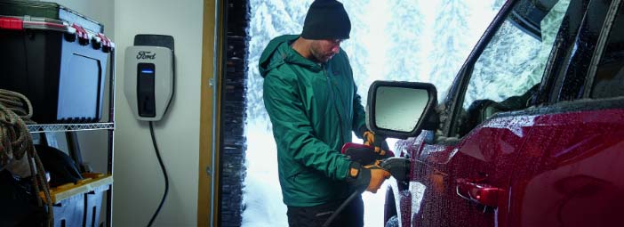 Man inside a garage plugging in an F150 Lightning to charge