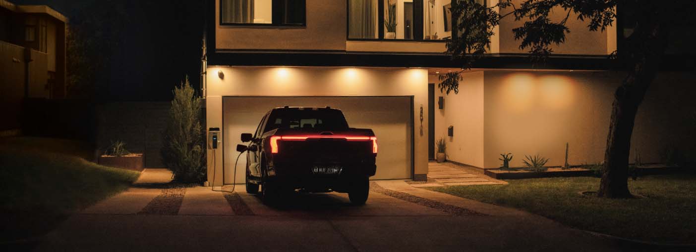 F150 Lightning parked in front of a home while charging.